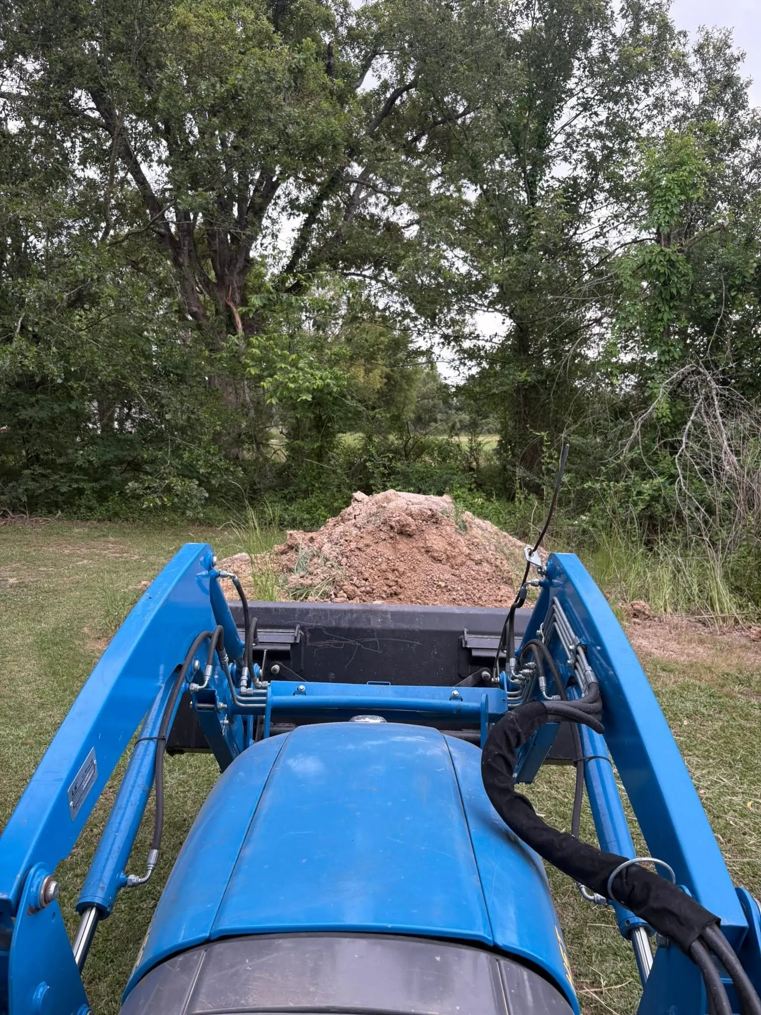 Tractor front loader moving a pile of dirt for driveway work